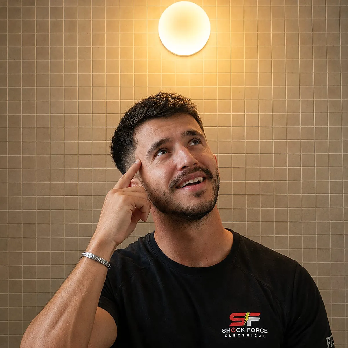 Shock Force electrician working beneath a newly installed wall light